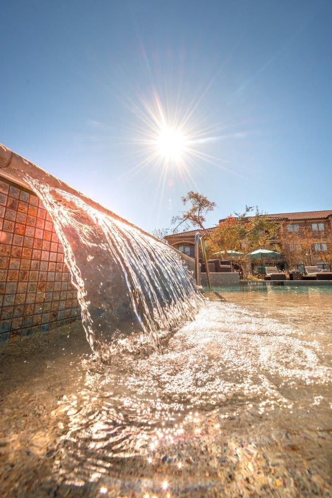 a water feature with the sun shining in the background