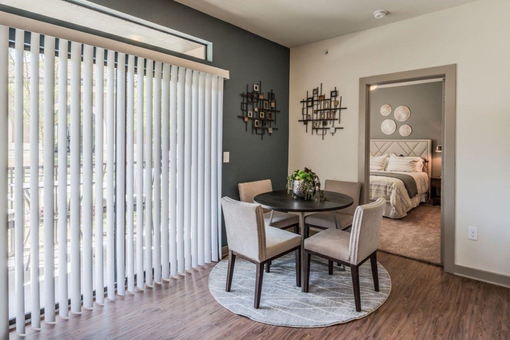 a dining area with a round table and two chairs and a bedroom in the background