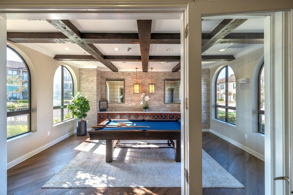 a game room with a pool table and a wall of windows
