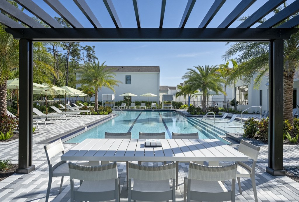 Argos by Soltura Rental Homes pool with white tables and chairs and a building in the background