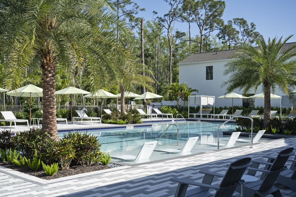 Argos by Soltura Rental Homes large pool with chairs and umbrellas and a building in the background