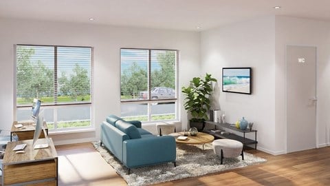 A living room with a blue couch and a large window with a view of trees.