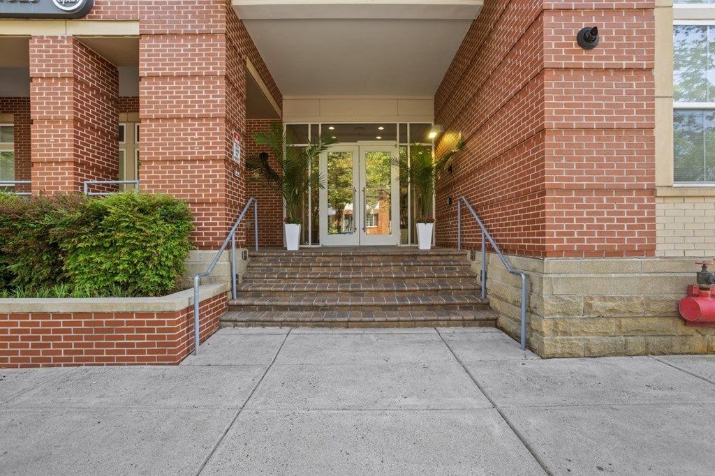 A red brick building with a glass door and steps leading up to it.