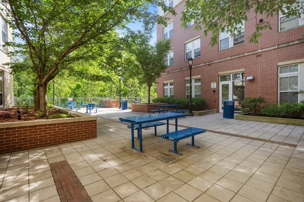 A sunny day at a brick building with a blue picnic table and benches.