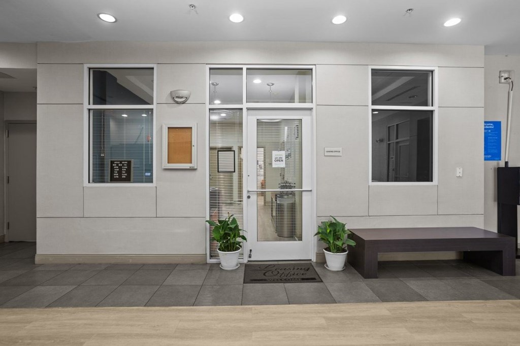 A white building with a glass door and a bench in front.