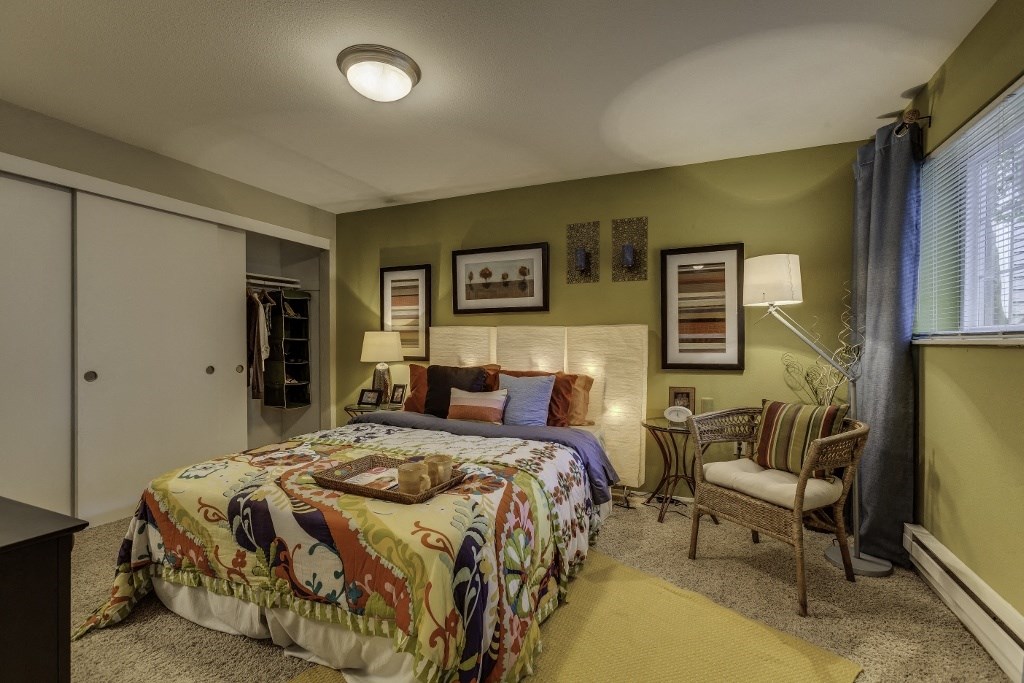 a bedroom with a bed and a chair and a window