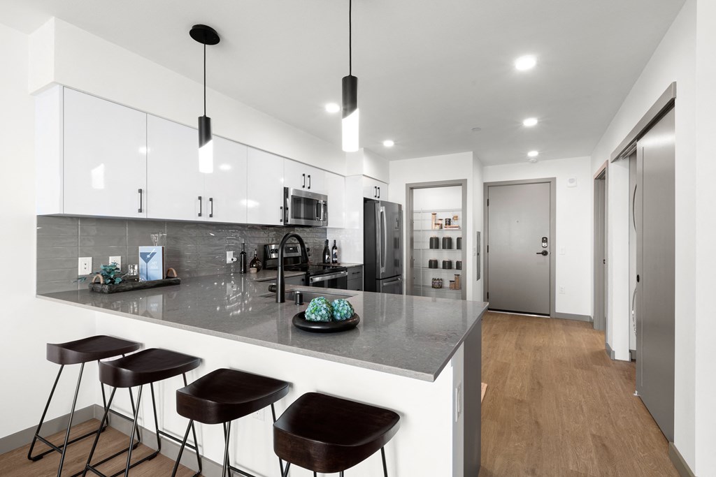 a kitchen with white cabinets and a large island with three stools