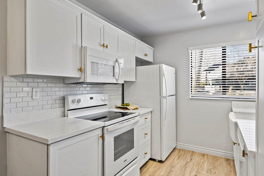 A white kitchen with a refrigerator, oven, and microwave.