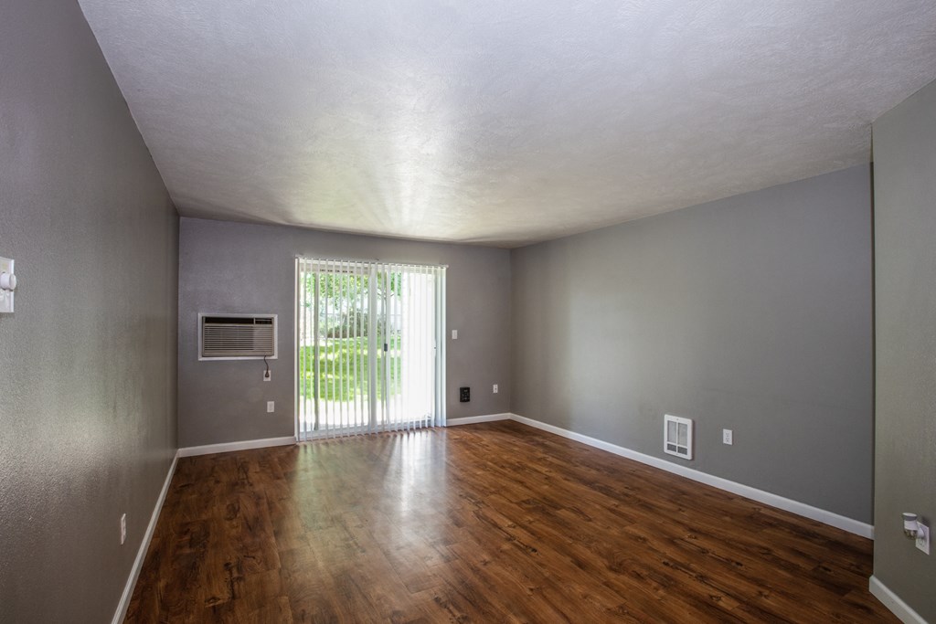 an empty living room with wood floors and a sliding glass door
