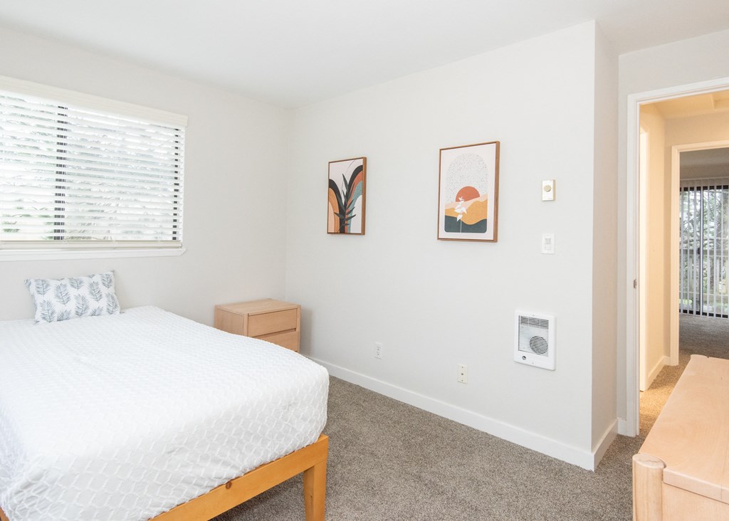 a bedroom with a white bed and two pictures on the wall