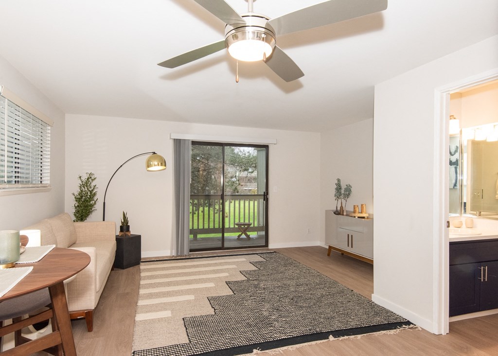 a living room with a ceiling fan and a sliding glass door to the backyard