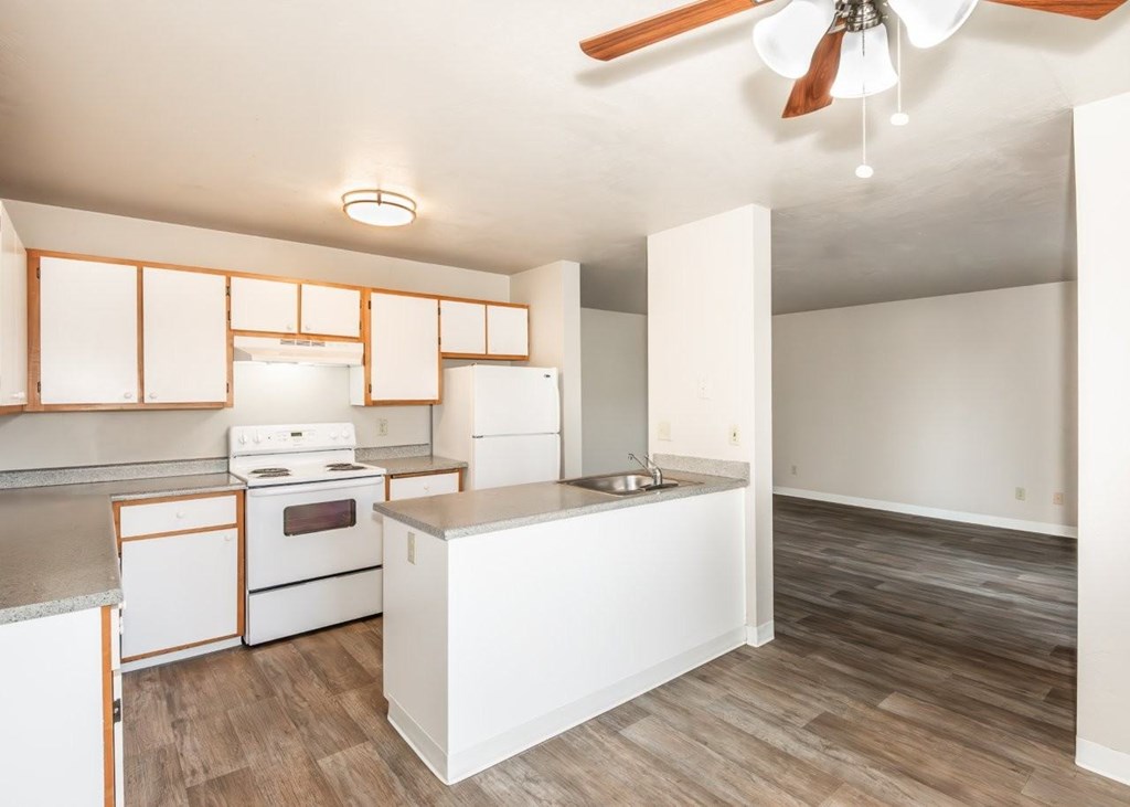 A kitchen with white appliances and wooden floors.