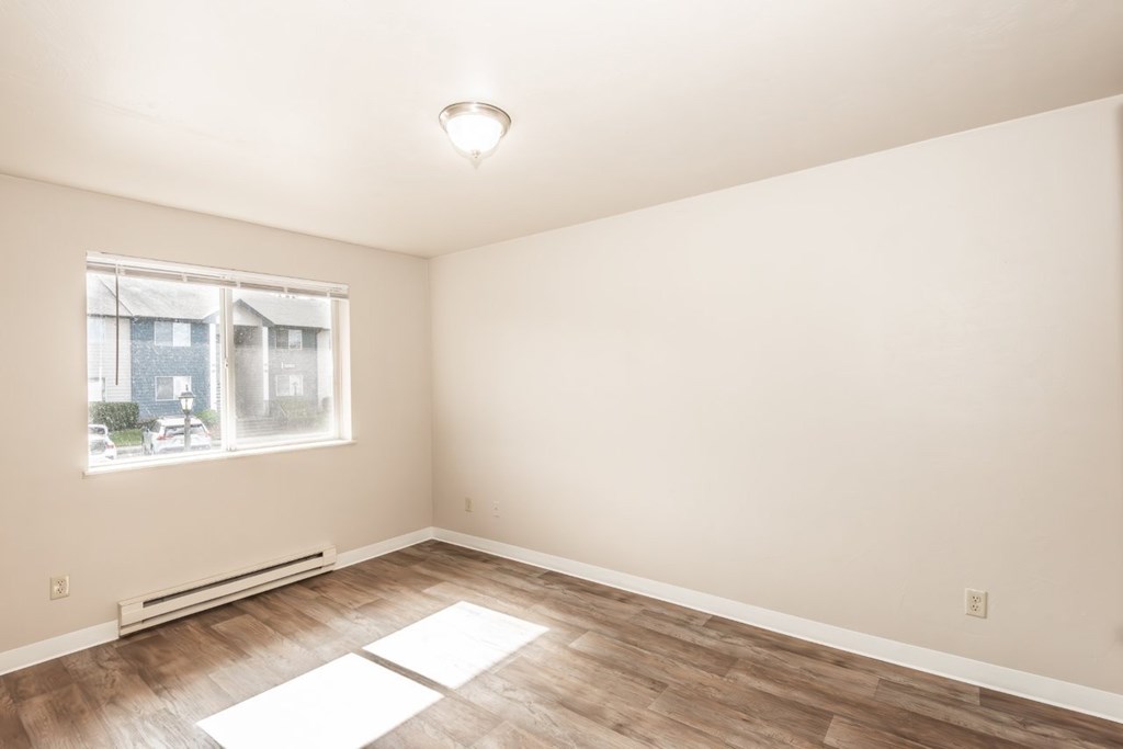 A room with a window and a radiator on the floor.