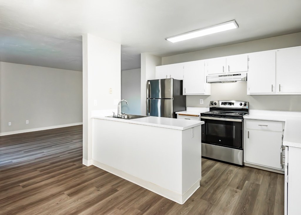 A kitchen with white cabinets and a wooden floor.