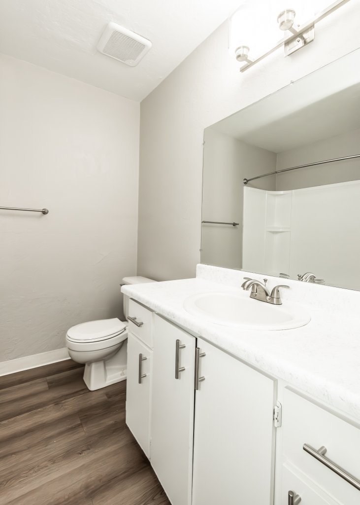 A white bathroom with a toilet, sink, and mirror.