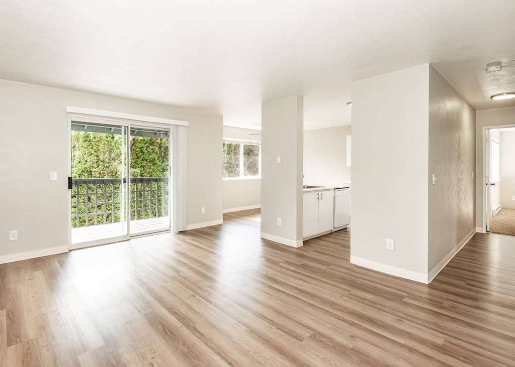 A spacious living room with wooden floors and white walls.