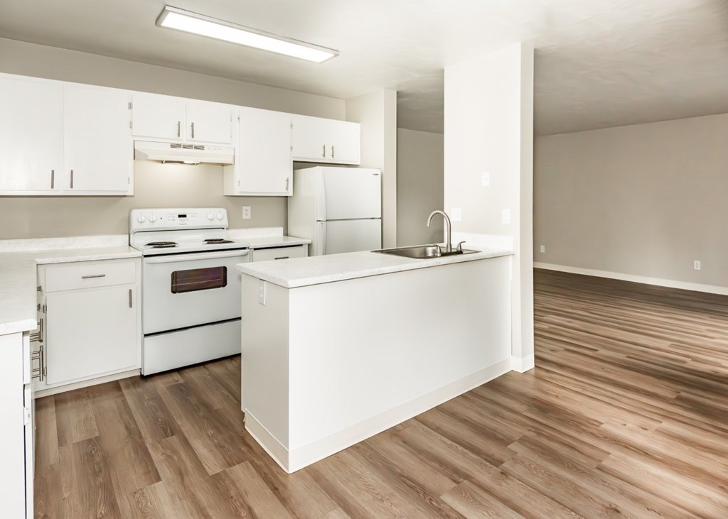 A kitchen with white appliances and wooden floors.