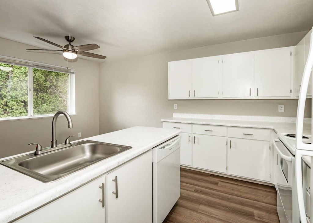 A kitchen with white cabinets and a stainless steel sink.