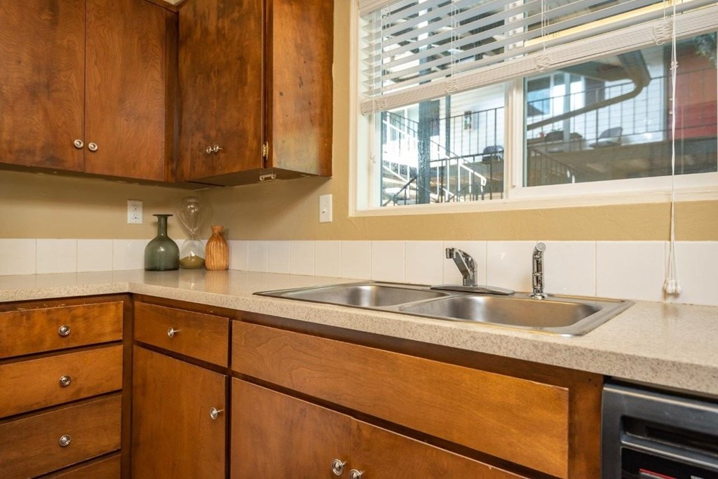 A kitchen with wooden cabinets and a stainless steel sink.