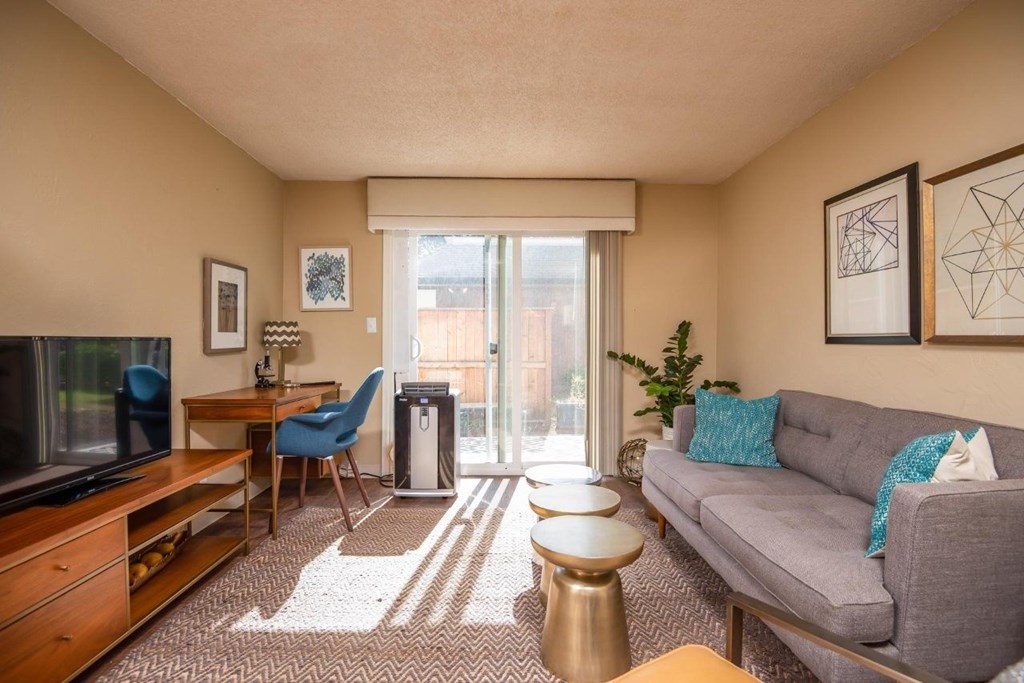 A living room with a grey couch, a television, a chair, and a table.