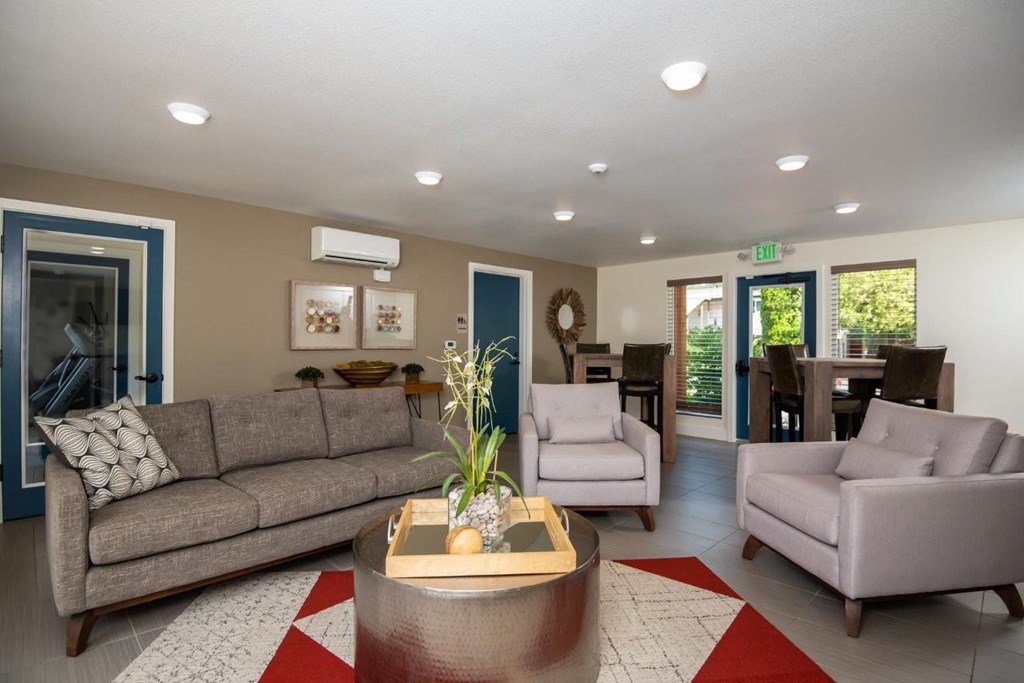 A living room with a grey couch, a coffee table, and a wreath on the wall.
