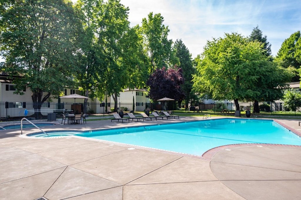 A large swimming pool surrounded by trees and chairs.