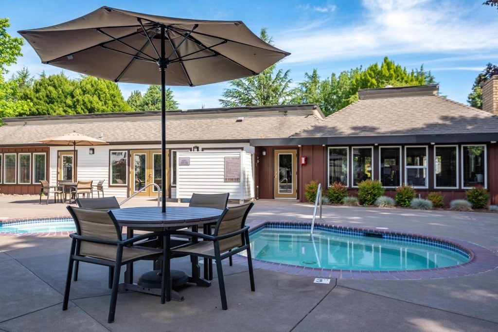 A patio with a table and chairs and an umbrella is shown.