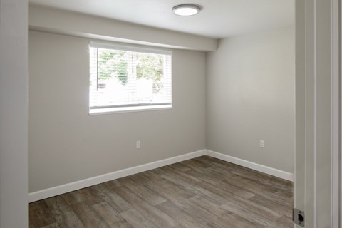 A room with a window and wooden flooring.