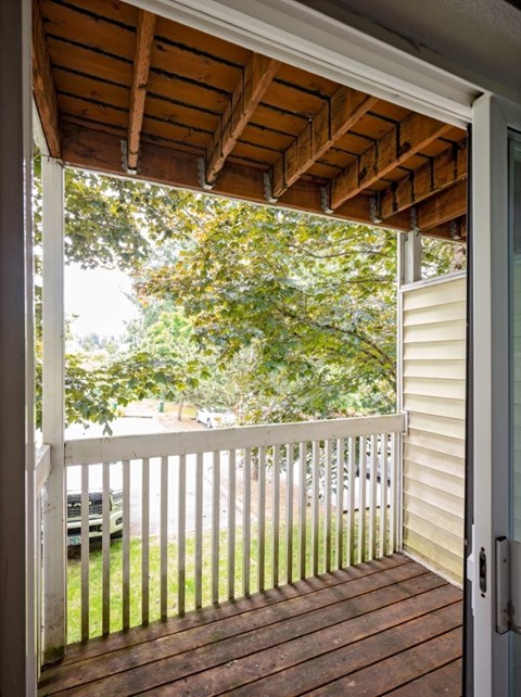 A wooden deck with a sliding glass door leading to a backyard.