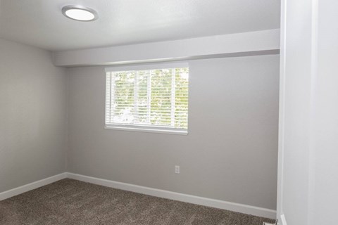 A room with a window covered by white blinds.