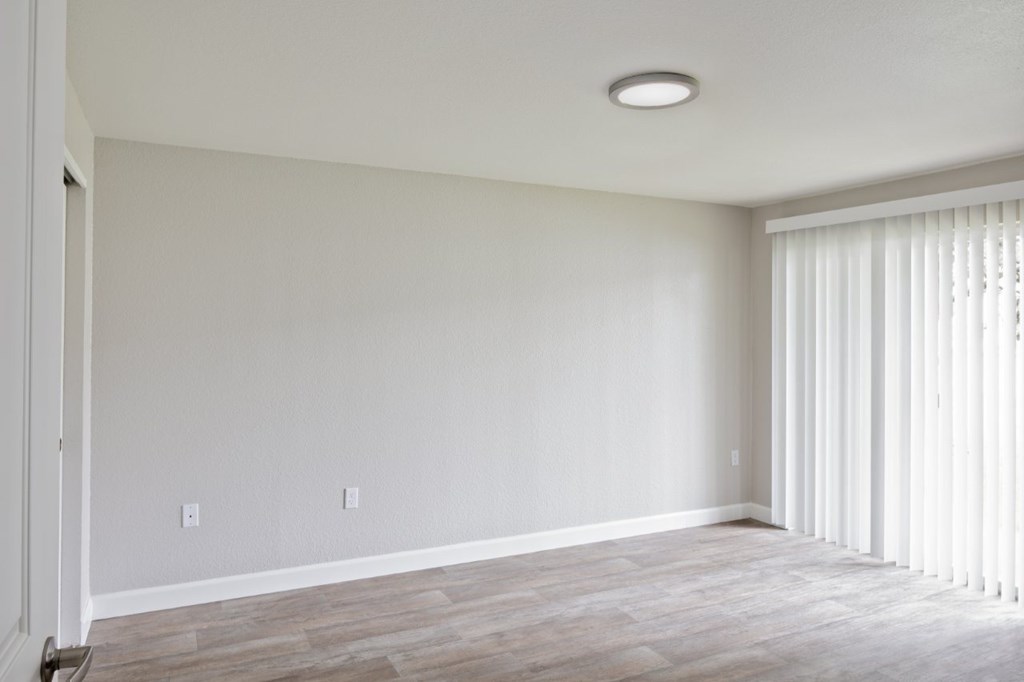 A room with a light on the ceiling and a window with blinds.