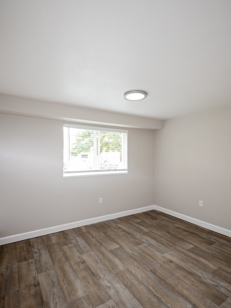 A room with a window and wooden flooring.