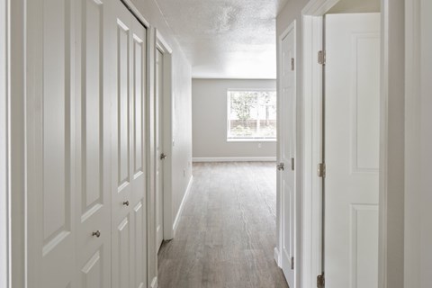 A long hallway with white doors and a window.