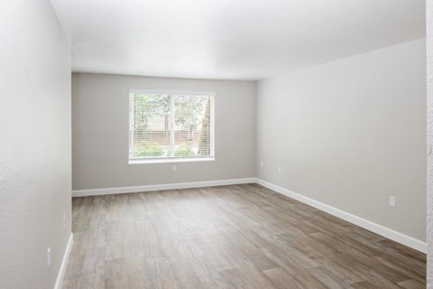 Empty room with a window and wooden flooring.