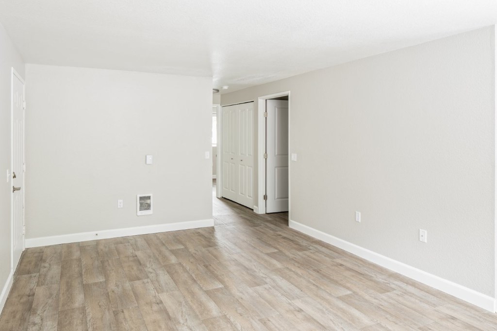 A room with light wood flooring and white walls.