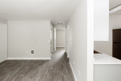 A long, empty hallway with wood flooring and white walls.