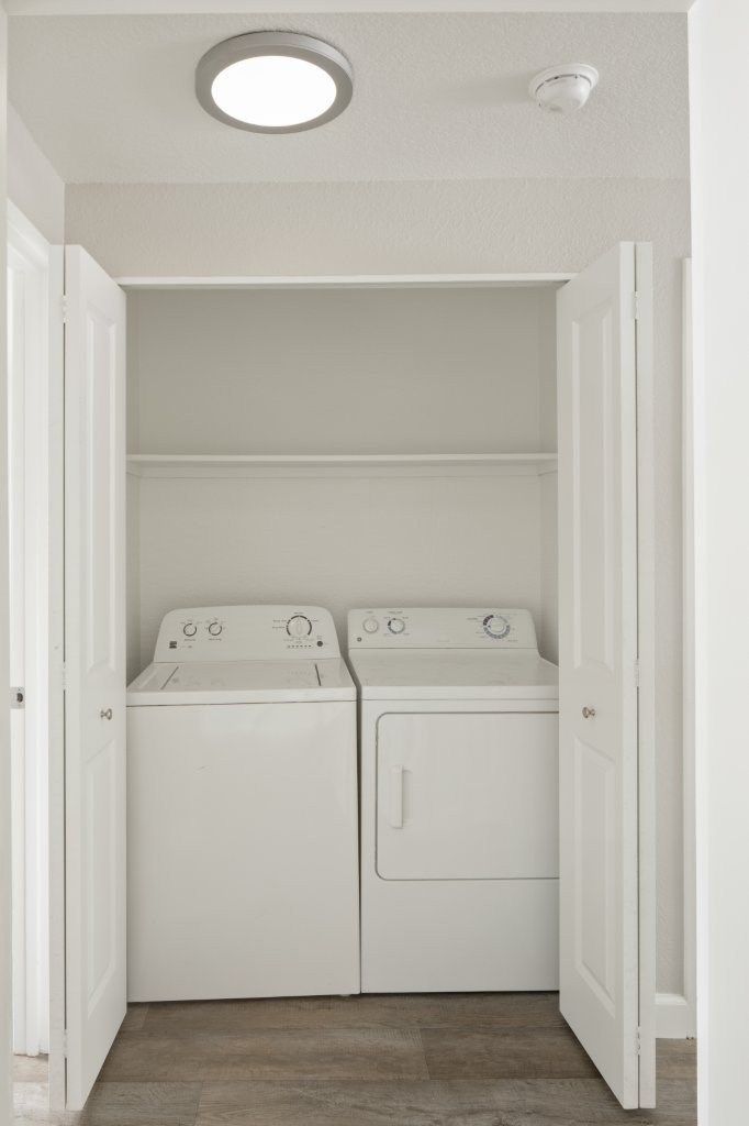 Two white washing machines in a small laundry room.