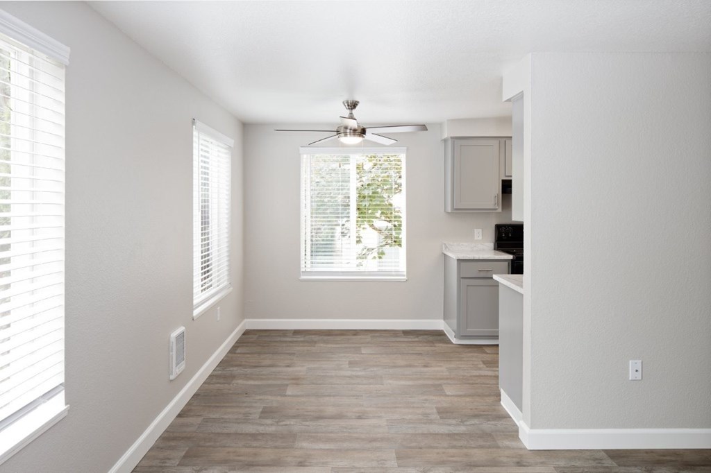 A room with a ceiling fan and a window with blinds.