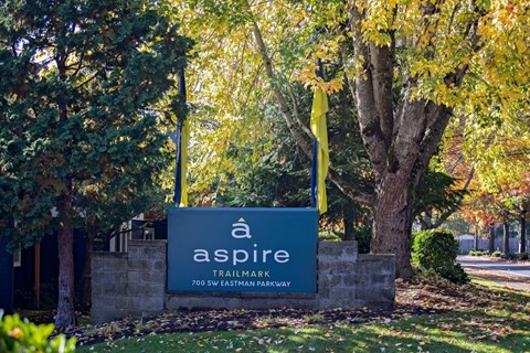 A sign for Aspire Trailmark is shown in front of a tree.