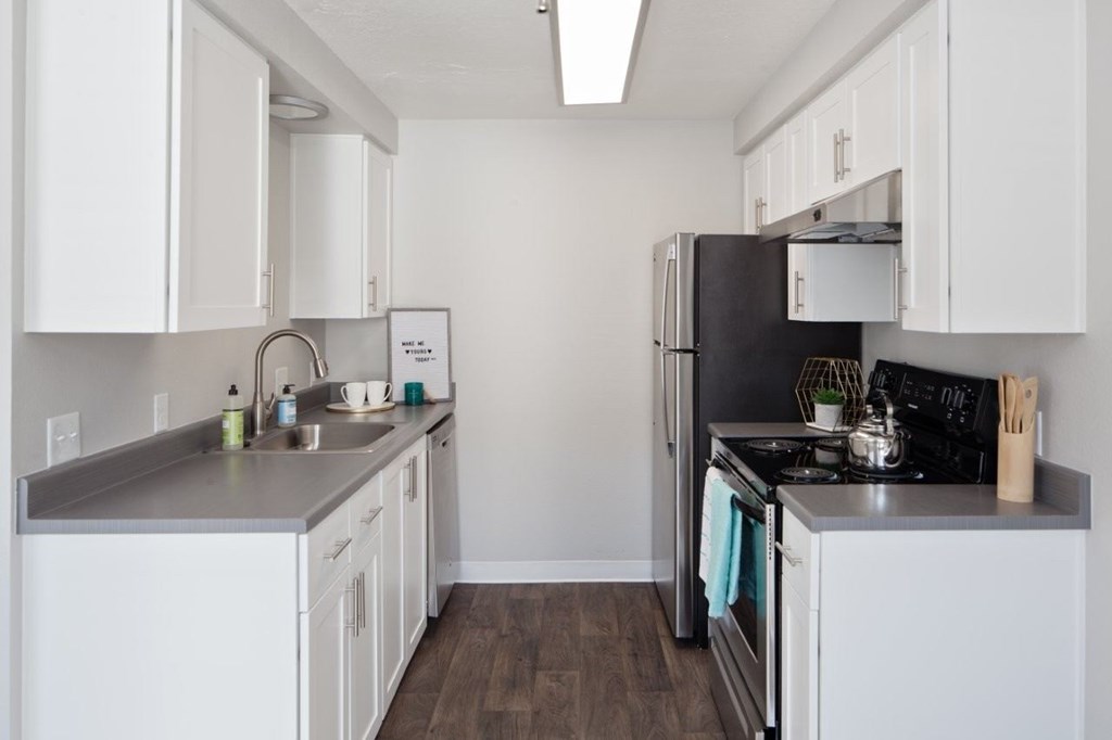 A kitchen with white cabinets and a black refrigerator.