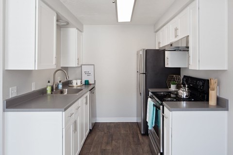A kitchen with white cabinets and a black refrigerator.