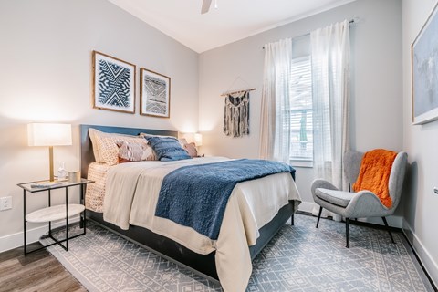 A bedroom with a bed, chair, and two wall hangings.