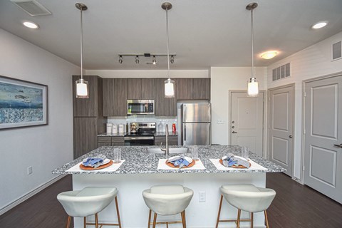 a kitchen with a marble counter top with white chairs