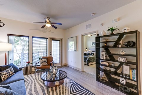 A living room with a ceiling fan and a glass coffee table.