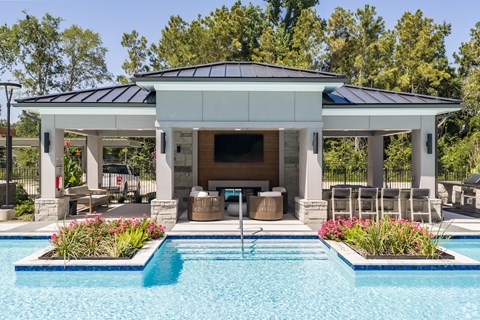 A pool house with a black roof and white columns.