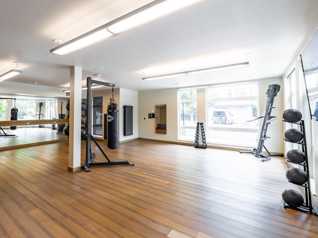 A gym with a punching bag, weights and exercise equipment.