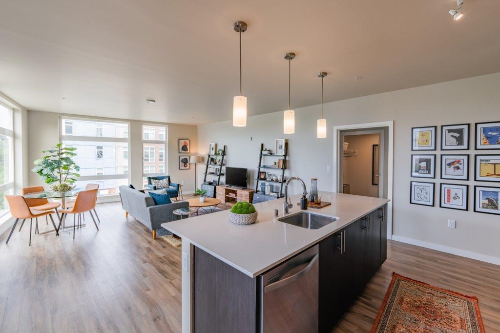 A modern kitchen with a large island and a dining area with chairs.
