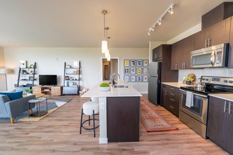 A modern kitchen with dark wood floors and stainless steel appliances.