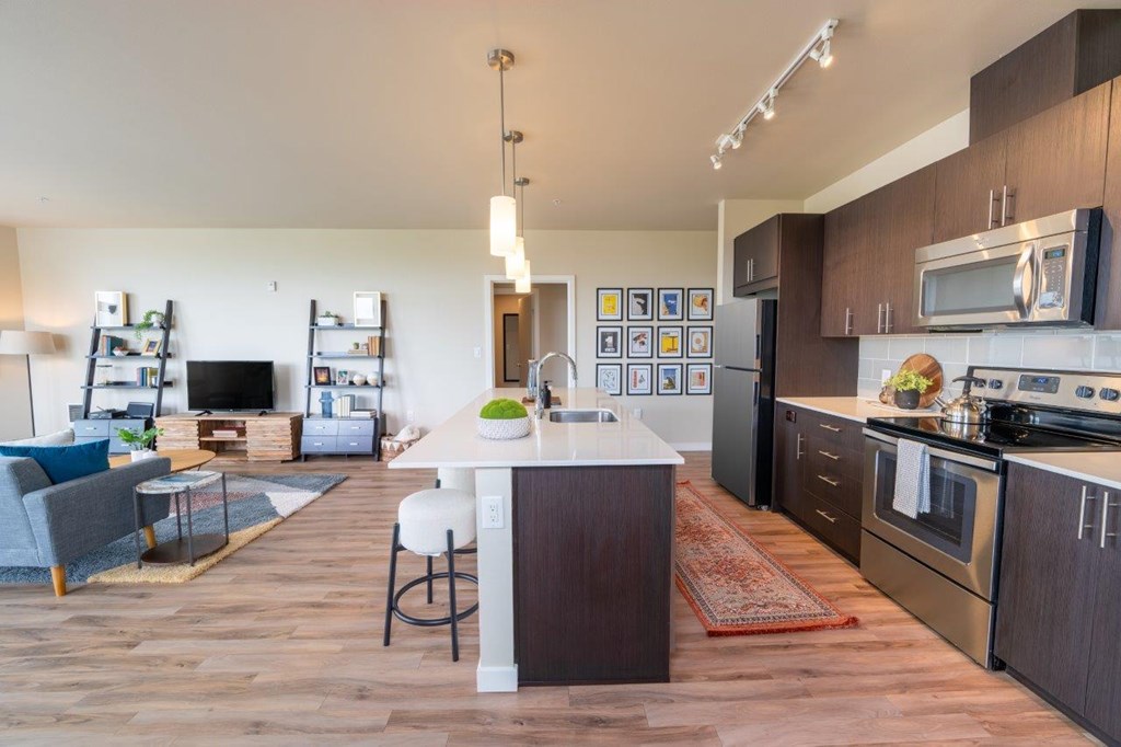A modern kitchen with dark wood floors and stainless steel appliances.