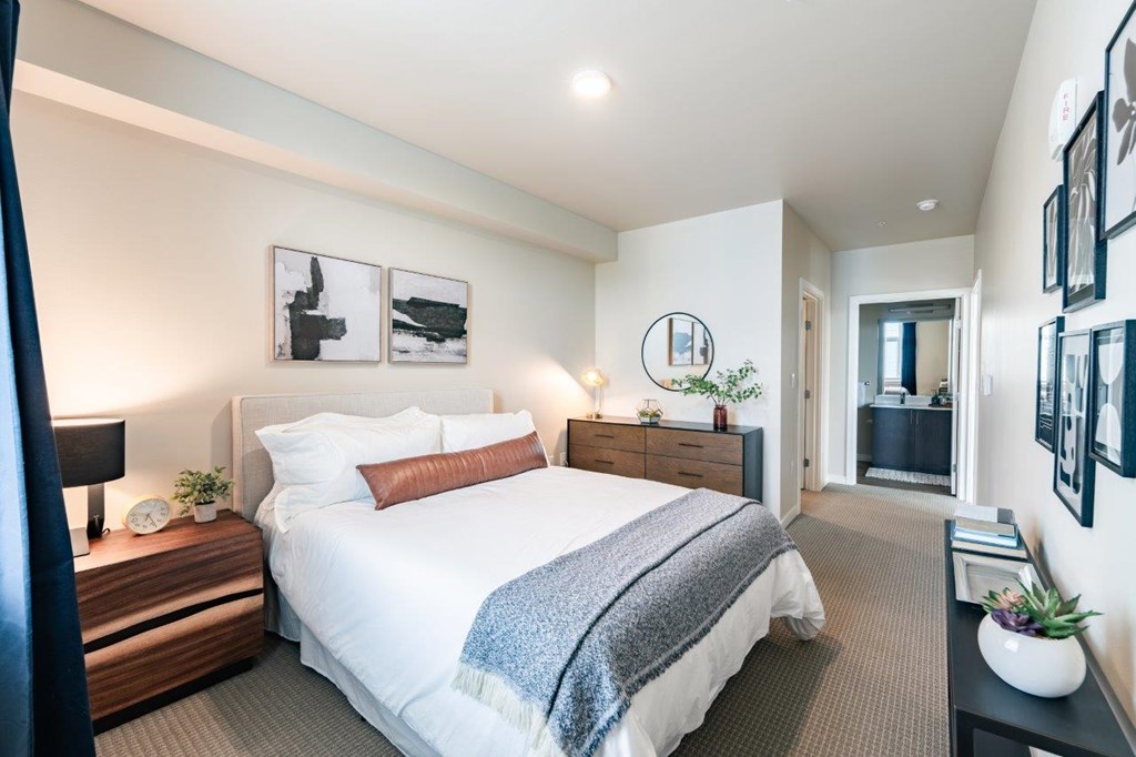 A bedroom with a large bed and a nightstand with a lamp.